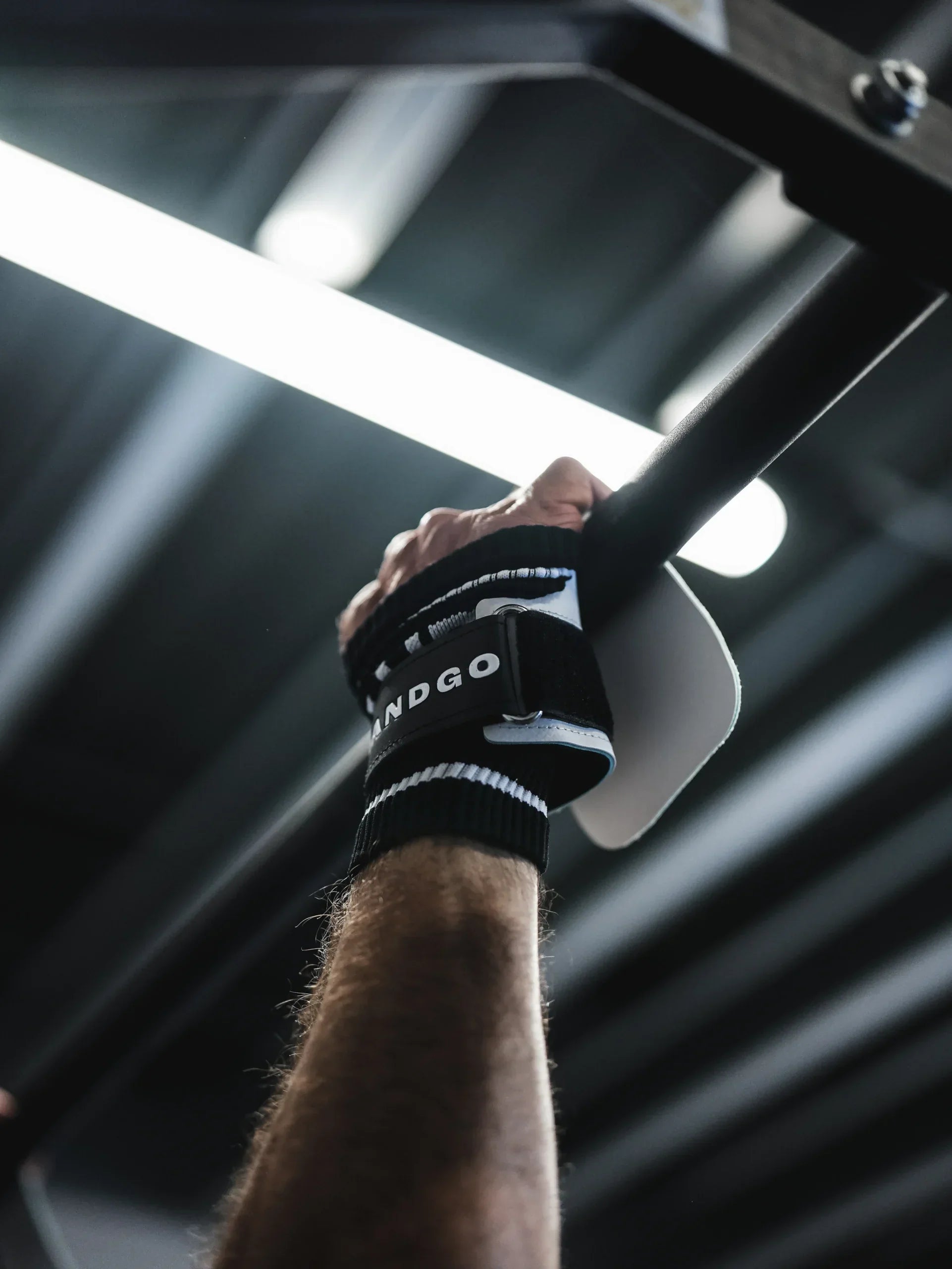 Athlète suspendu à une barre avec des maniques Powergrip Fusion blanches, sans magnésie