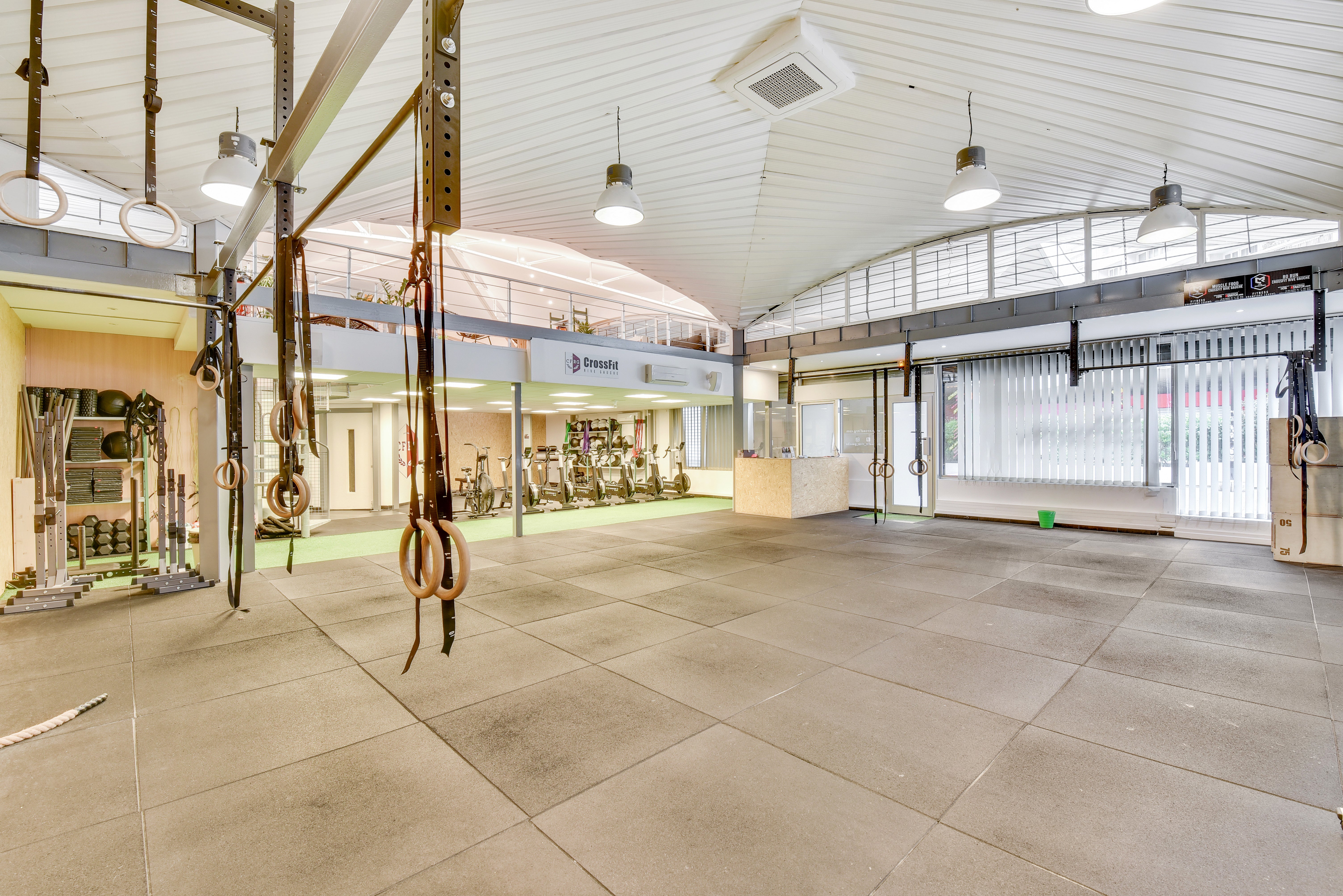 Salle d'entraînement de la box partenaire Rive Gauche à Paris 13, avec anneaux de gymnastique, racks et vélos